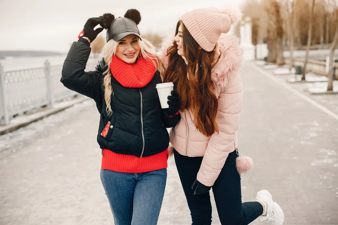 Сравнение короткого пуховика и зимней куртки Две девушки в зимней одежде: черная куртка и розовый пуховик с мехом